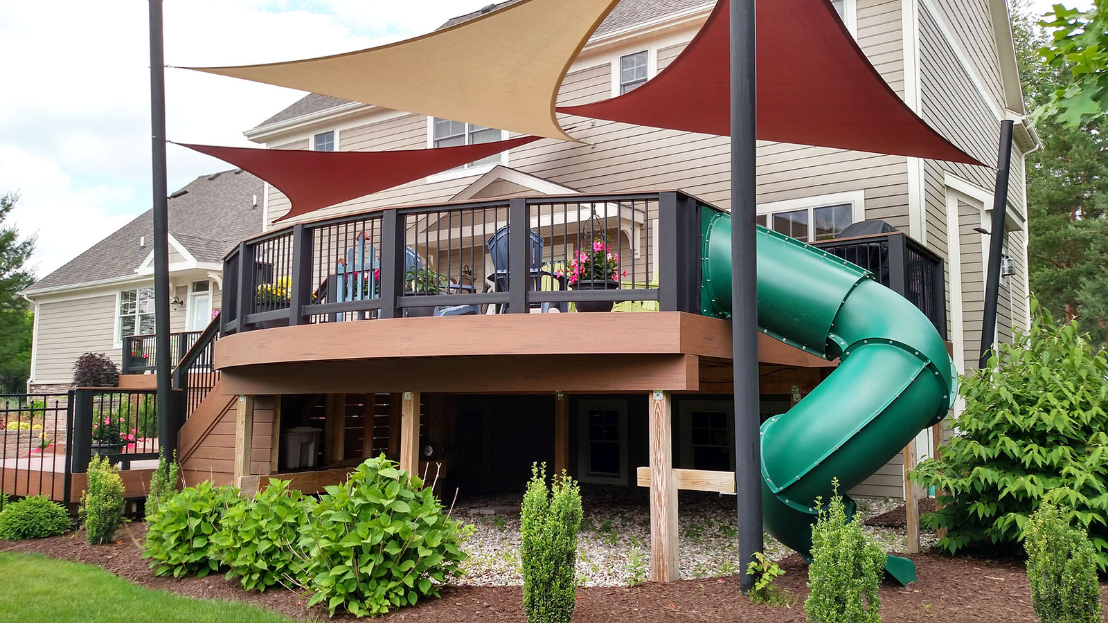A custom deck contractor project from Signature Decks & Construction. A deck with a kids slide attached to the side.
