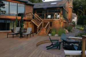 As Grand Rapids Deck Builders, Signature projects are unique to each homeowner. A deck, sunroom, and fire pit combination extending the back of a house.