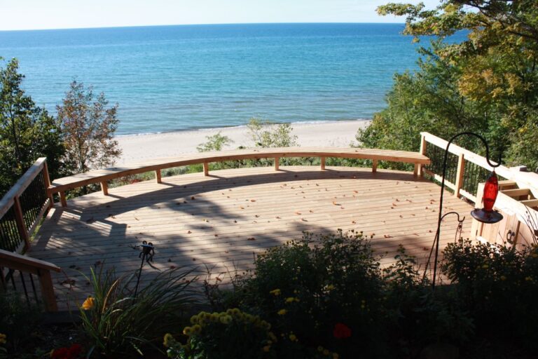 Forget standard backyard deck shapes. Signature creates custom decks that meet the needs of our customers. The view from the second tier of an elevated deck built along the back of a house near the shores of Lake Michigan. The deck is curved to fill the space between the trees.
