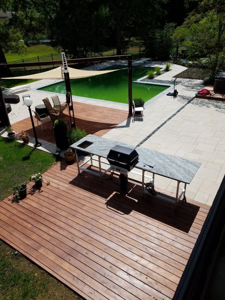 Signature knows the carpenter vs contractor debate well. While one is good for small projects, our team can design a more complete project. A backyard with two separate deck platforms, one with a sail covering patio furniture, the other with a grilling station.
