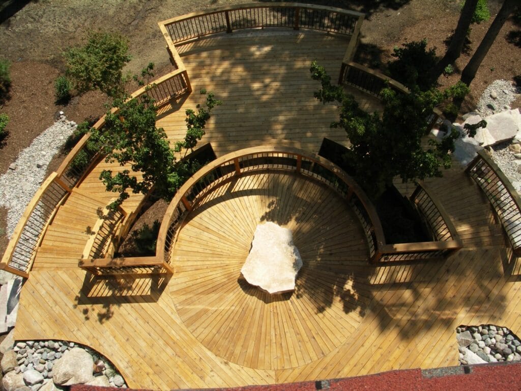 Outdoor circular deck with stone in the center with two stories by Signature Decks.