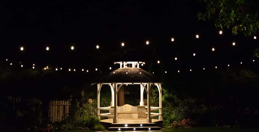 Patio lighting ideas take many forms, including (as shown) string lights around a Gazebo at night, or lights within the steps of a walkway.